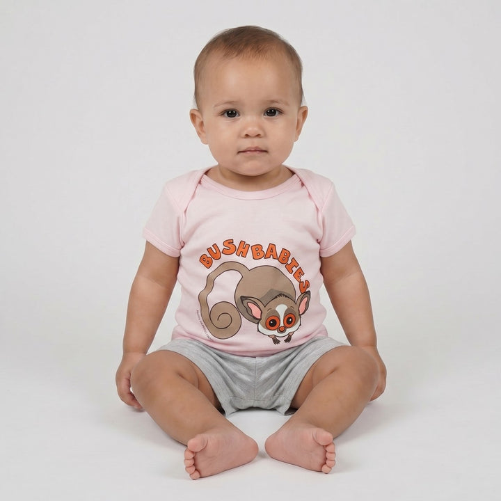 Infant in a pink short-sleeve Bushbaby T-Shirt with a graphic and orange text, paired with grey shorts, front view.