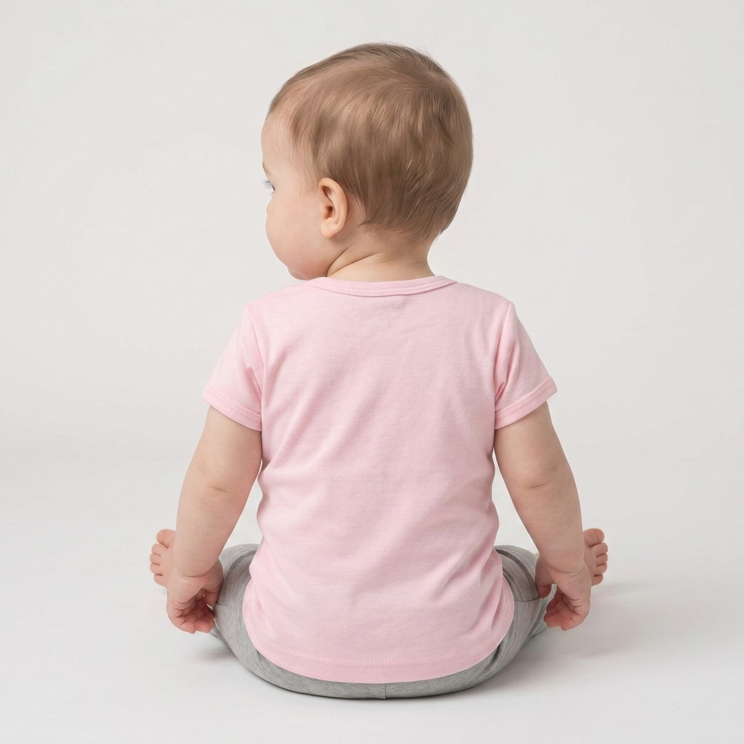 Bushbaby T-Shirt in pink, worn by a baby and photographed from the back, paired with simple grey pants.