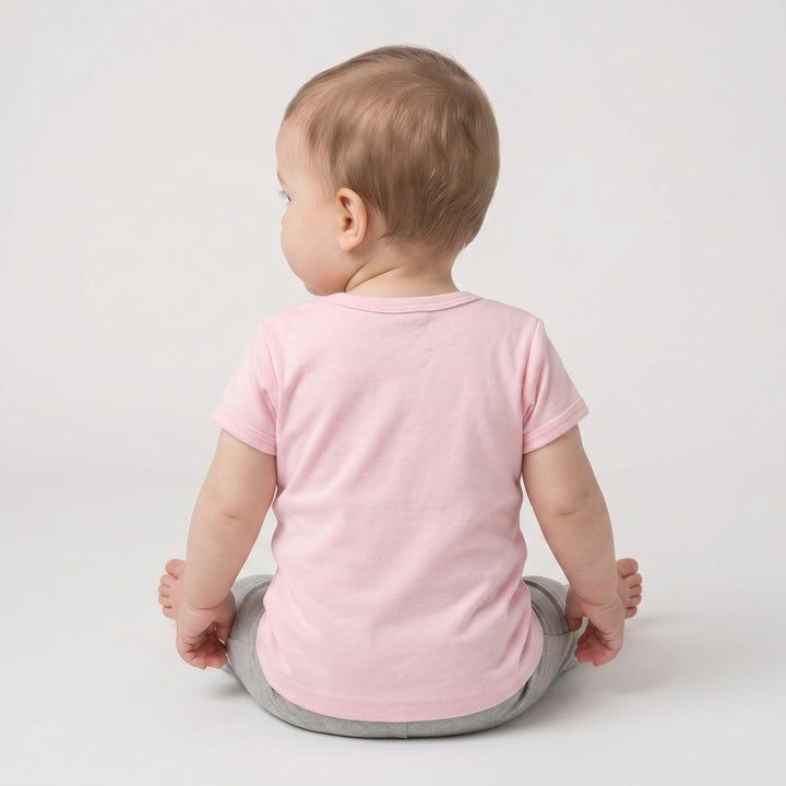Bushbaby T-Shirt in pink, worn by a baby and photographed from the back, paired with simple grey pants.