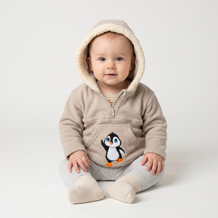 A stone beige fleece infant half-zip hoodie with a cream sherpa-lined hood and an adorable penguin graphic on the front