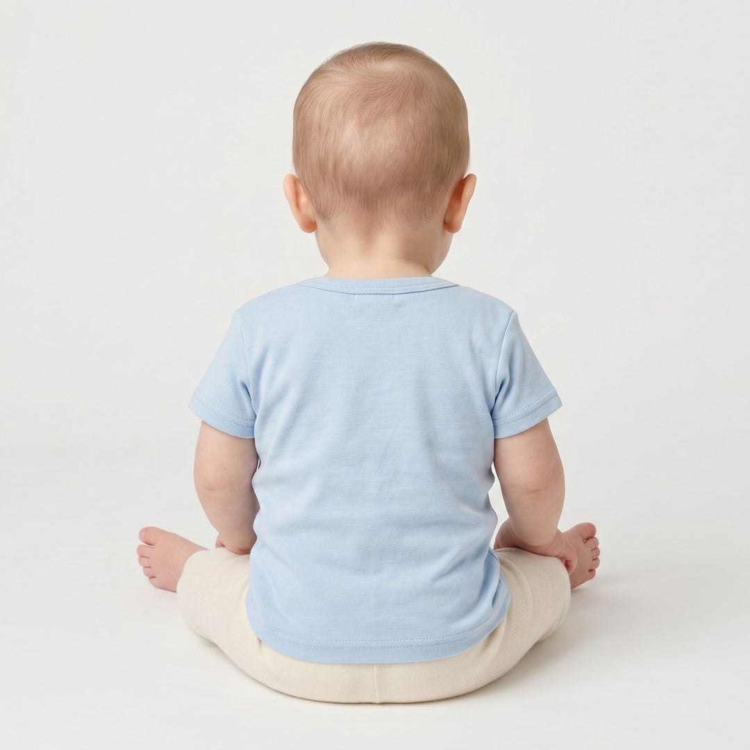 Light blue infant short-sleeve t-shirt with a crew neck, seen from the back on a baby wearing cream leggings.