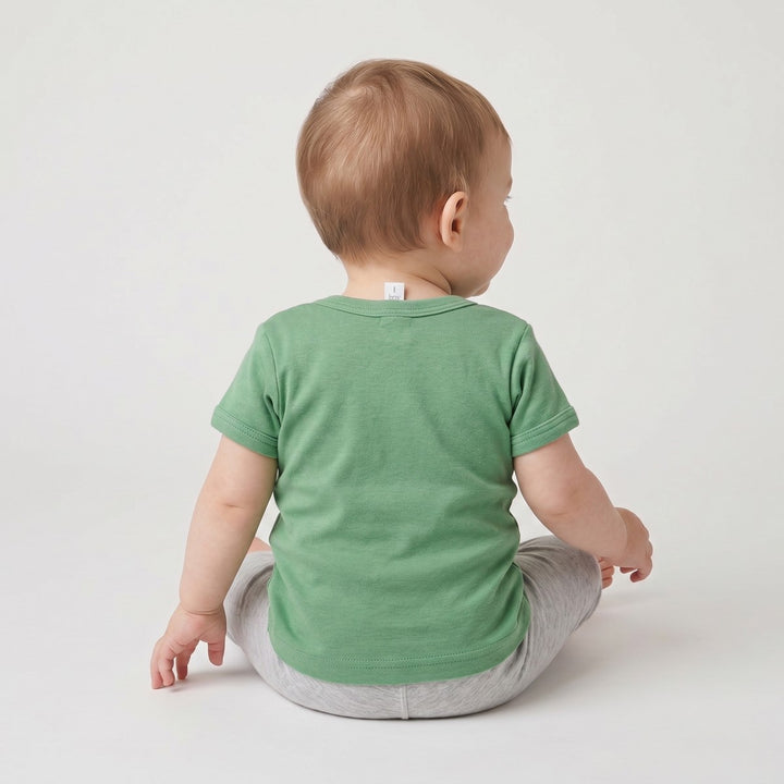 Back view of a baby wearing a plain green short-sleeved Lion T-shirt, made from soft cotton fabric.
