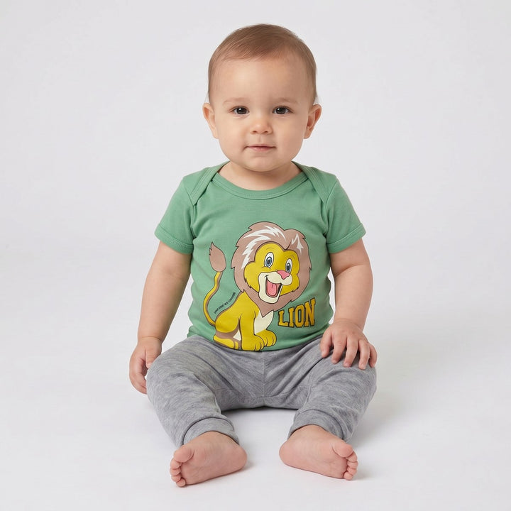 An infant baby wearing a green short-sleeved t-shirt with a yellow cartoon lion graphic and grey pants, photographed from