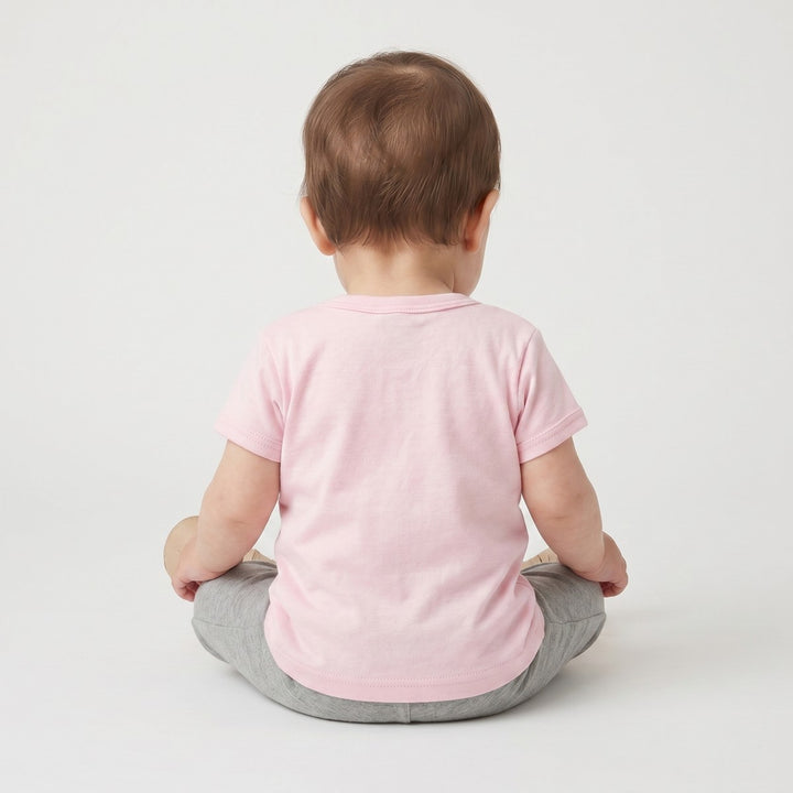 Pink short-sleeve Lion T-Shirt for baby, seen from the back, worn with gray leggings and neutral moccasin shoes.